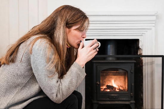 devon resident sipping tea next to her log burning stove